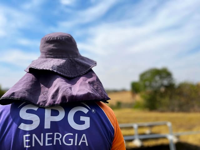 Técnico da SPG de costas, com a logo SPG Energia na camisa, em uma usina solar em solo