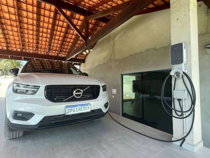 Carregador de carro elétrico na parede de uma garagem residencial, ao lado do carro